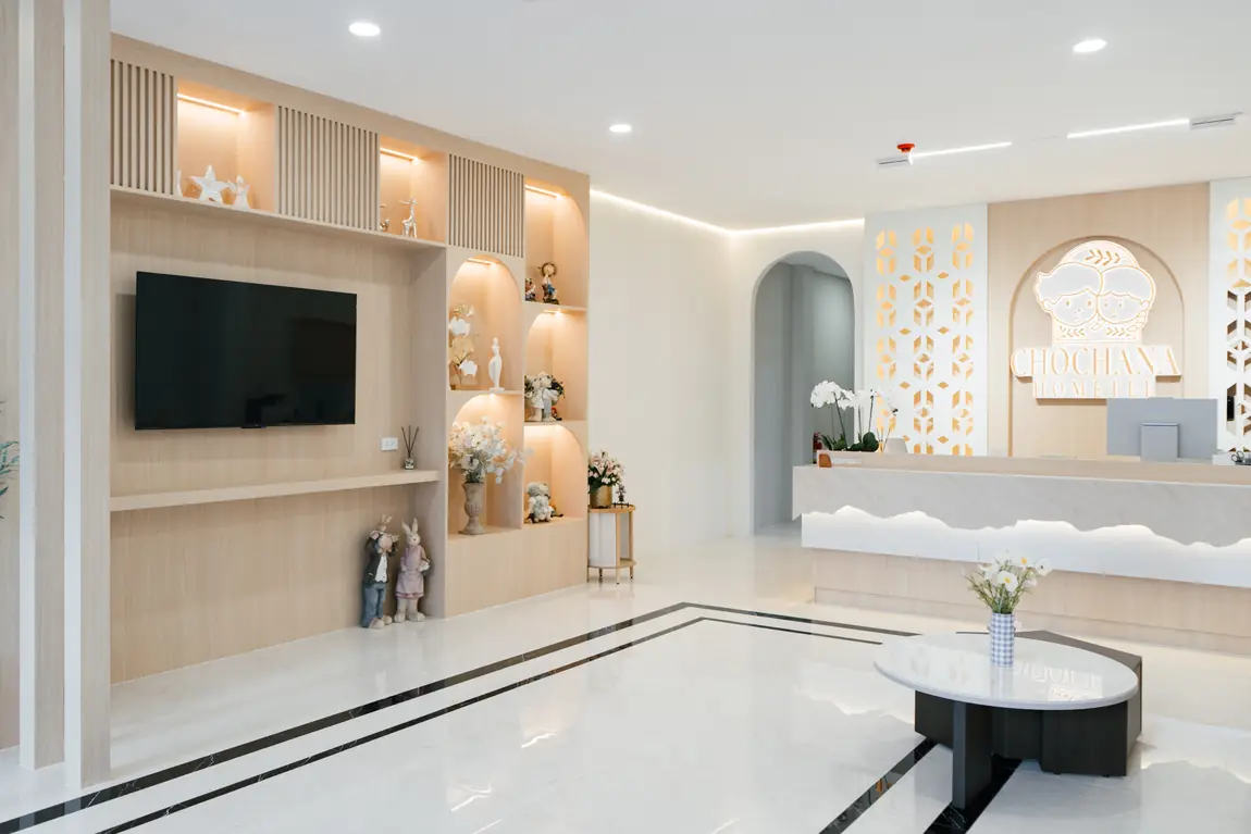 Lobby with lit arched shelves, a TV wall and the reception desk with its glowing ridge line