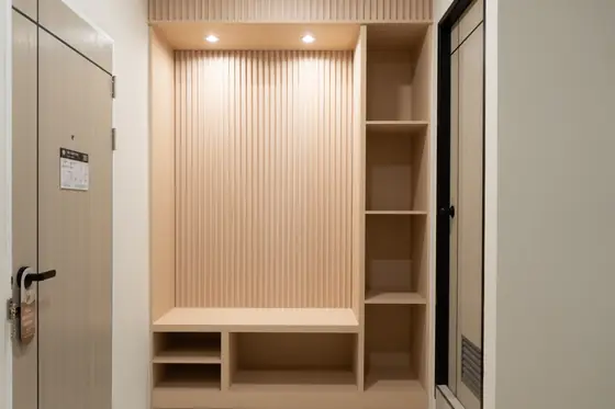 Open wardrobe with fluted wood panel, shelves and downlights inside a guest room