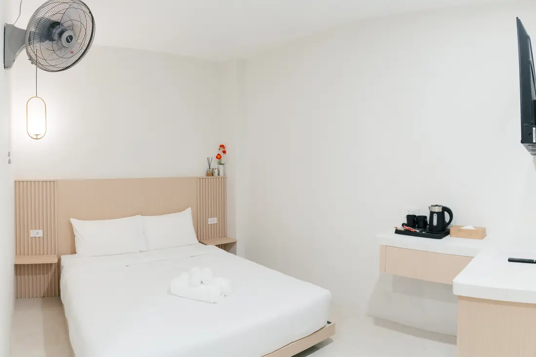 Standard Double with Fan room showing the double bed, wall fan and marble-top desk