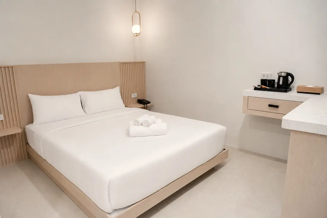 Superior Queen room with a queen bed, brass pendant lamp and a marble-top desk with kettle