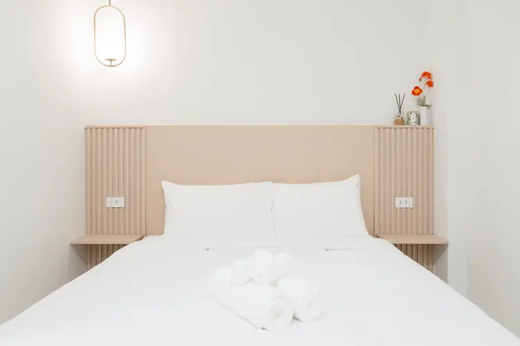 A Superior Queen bed with white linen, a blonde wood headboard and a brass pendant lamp